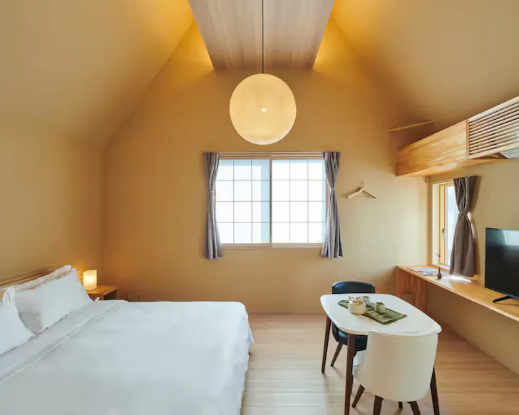 A sunshine yellow, light-filled bedroom at Reikyo Garden Studio Airbnb in Osaka.