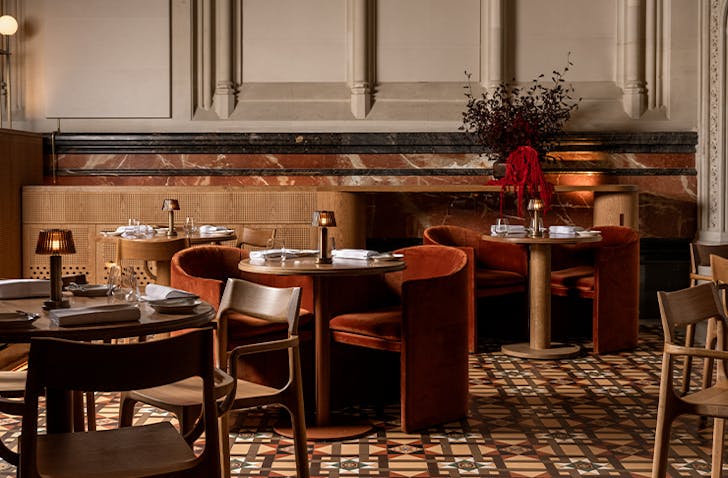 Several small round tables sit in a grand French restaurant in Melbourne.