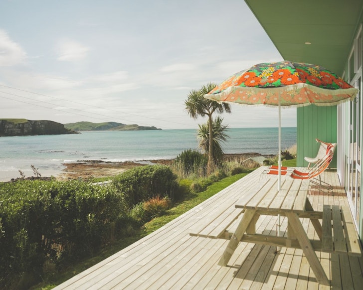 The deck with a water view at Retro Style House best beach house Airbnbs NZ