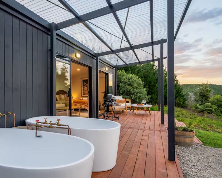 A view of the two outdoor baths on the deck at Ridge Retreat, one of the best cabin stays in New Zealand