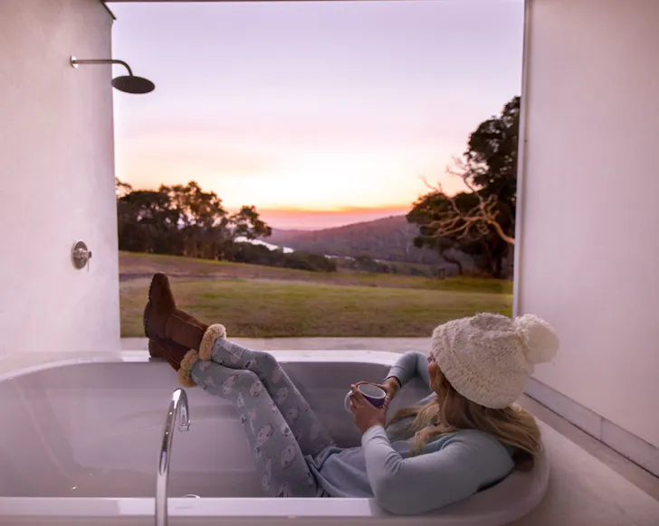 A woman in the outdoor bath at River Blue one of the best WA Airbnb stays
