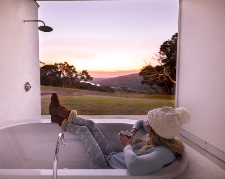 A woman in the outdoor bath at River Blue one of the best WA Airbnb stays