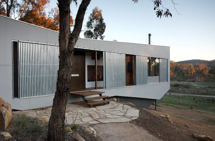 A long Airbnb with a metal-like exterior looks out to expansive views.