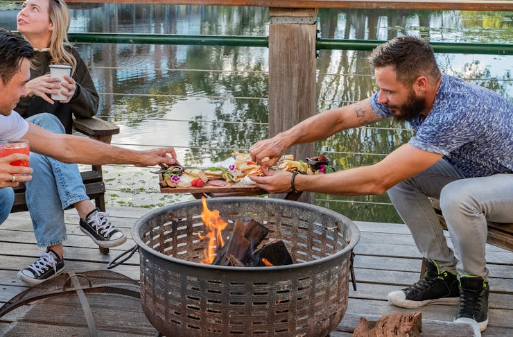 people gathered around a lakeside fire pit
