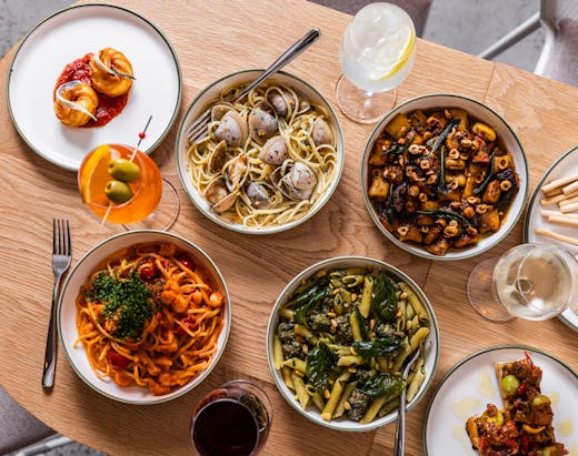 An aerial view of plates of pasta and drinks on a table. 