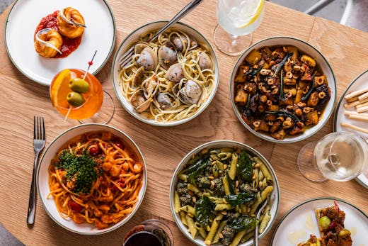 An aerial view of plates of pasta and drinks on a table.