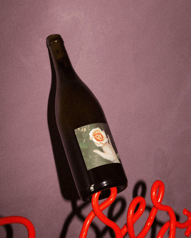 A bottle of wine labelled with a photo of a peach rose in Ophelia's hand. 