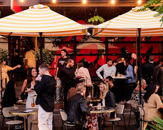 A group of people out front of a restaurant. 