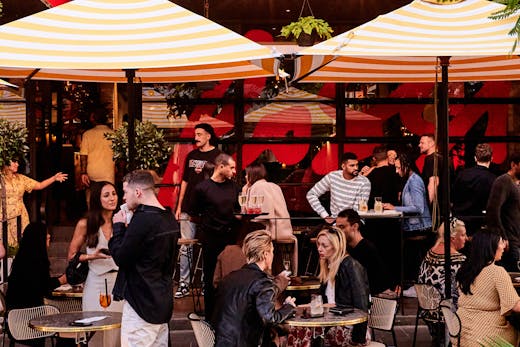 A group of people out front of a restaurant.