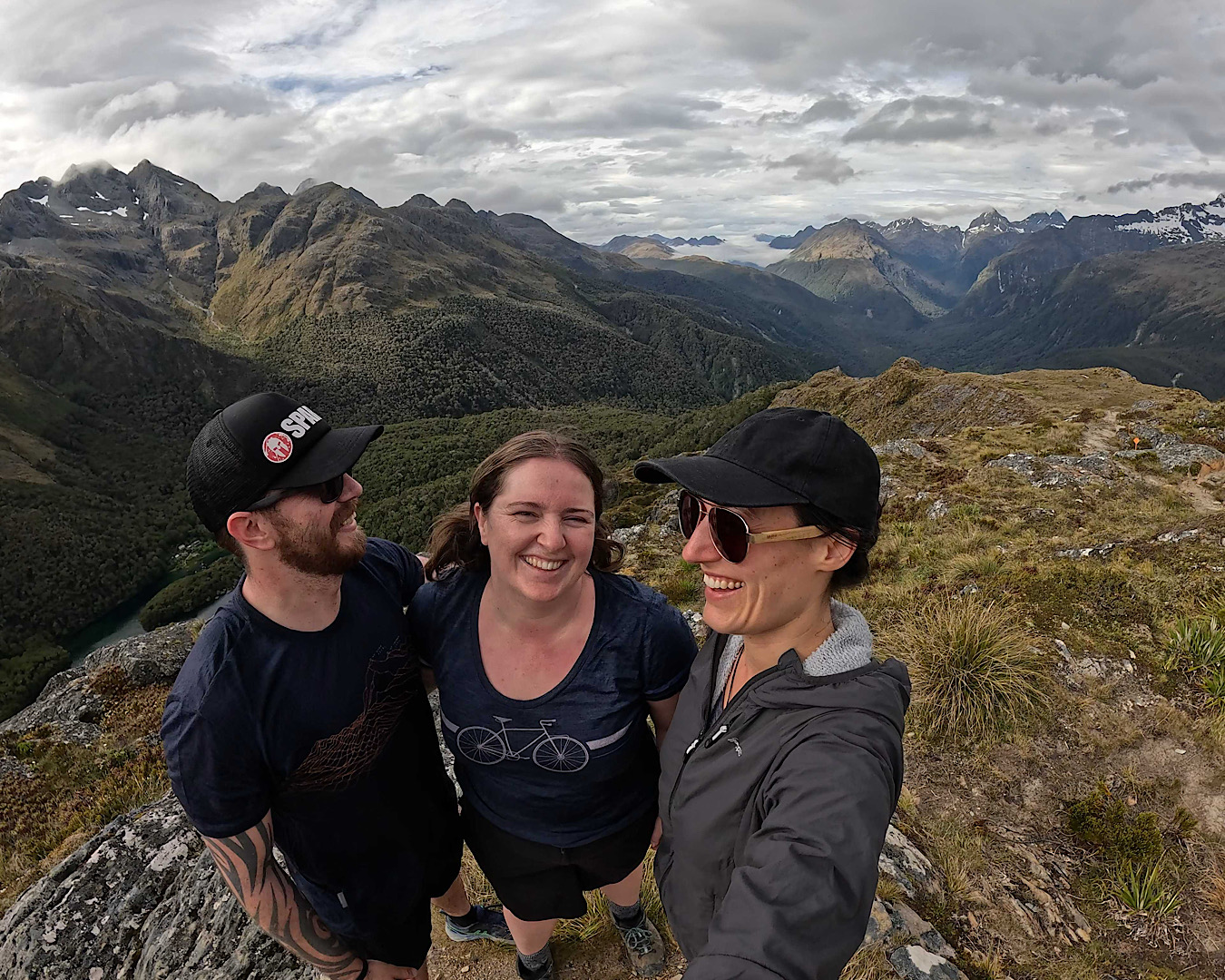 Three hikers take a selfie in front of stunning alpine terrain on the Routeburn. 