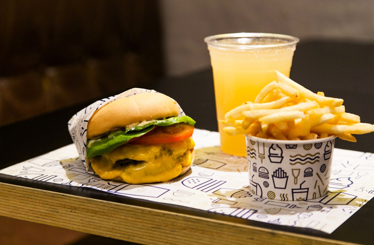 A burger sitting on a tray, dripping with cheese, considered one of the best burgers Melbourne has to offer in 2023.