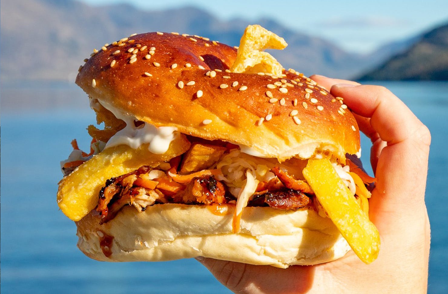 Hand holding a big loaded burger. 