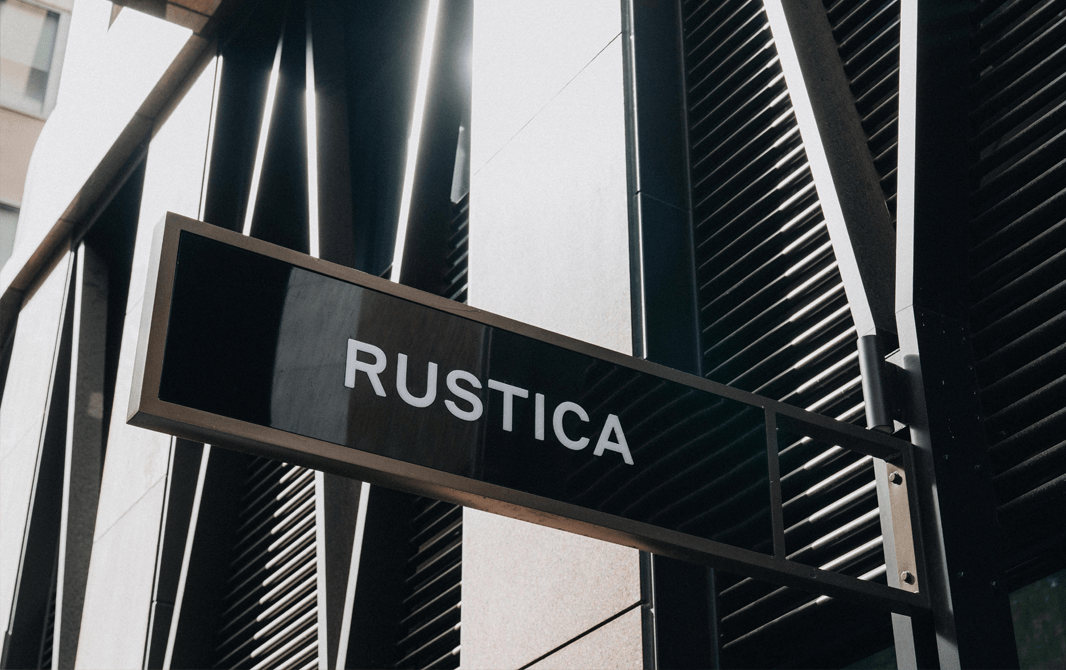 A black sign that reads 'Rustica' leading into one of the best cafes in Melbourne.