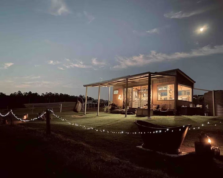 A view of Ryan’s Rest Tiny House at dusk, with firepit in the foreground, one of the best tiny houses in Australia