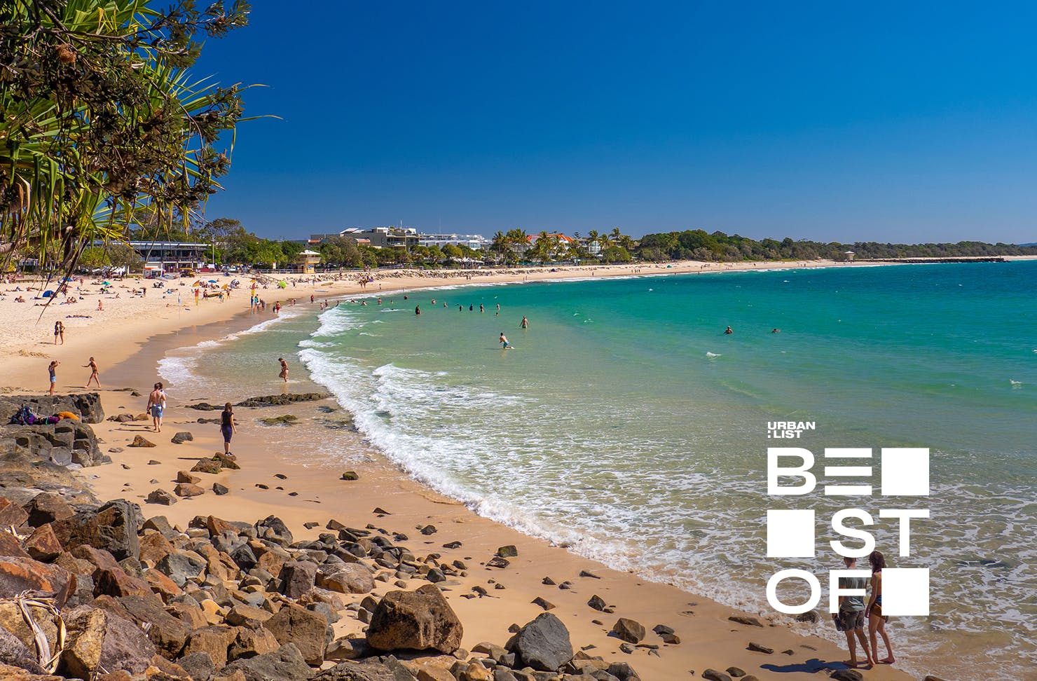 a long beach with blue skies and rolling water