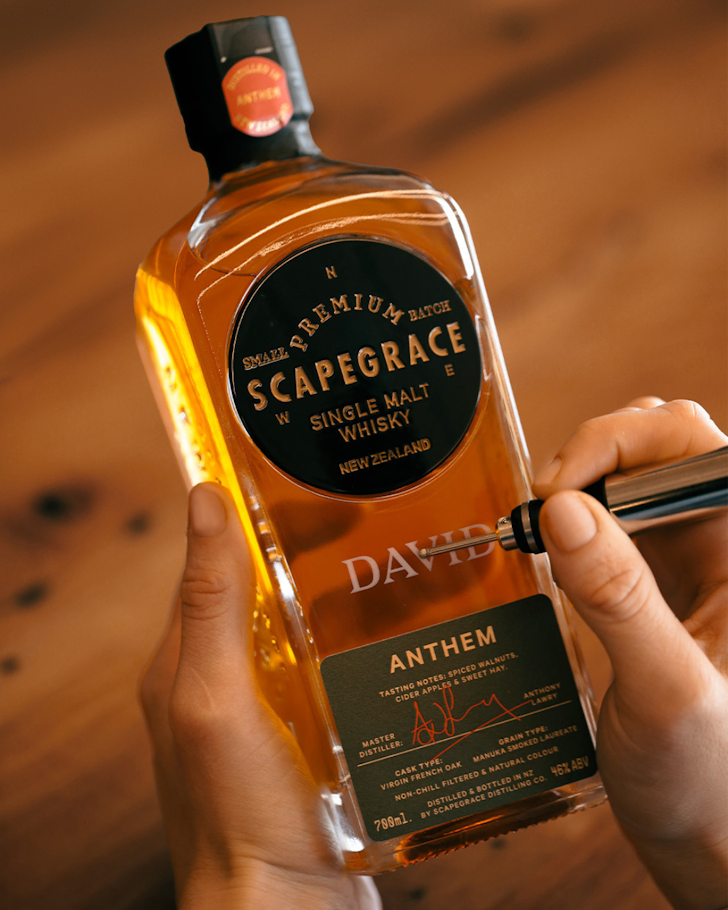 Someone engraves the name 'DAVID' onto a bottle of Scapegrace single malt.