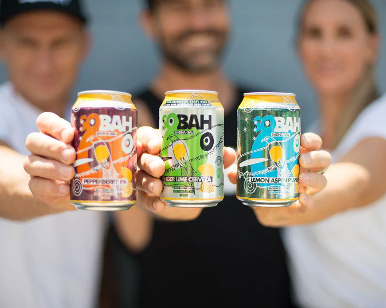 three people holding beer cans