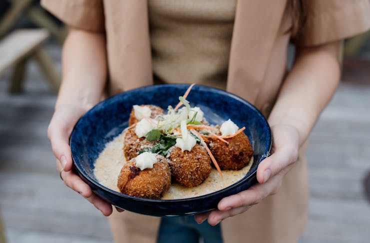 someone holding a plate of arancini balls