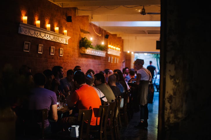A dining room with candles and people eating at one of the best late-night restaurants in Melbourne.