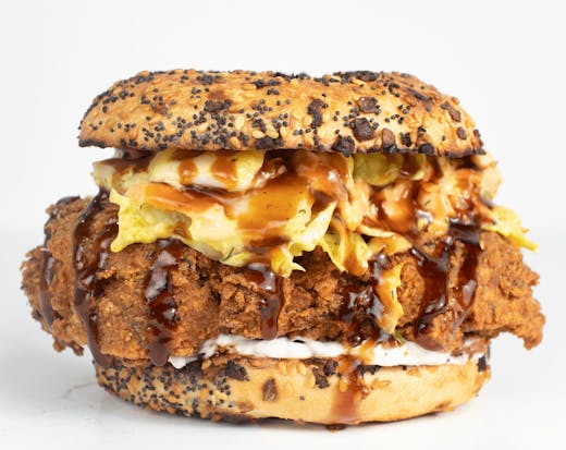 a fried chicken bagel with sauce dripping out. 