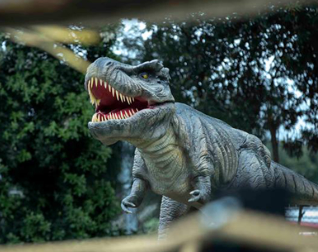 A dinosaur is seen through leaves.