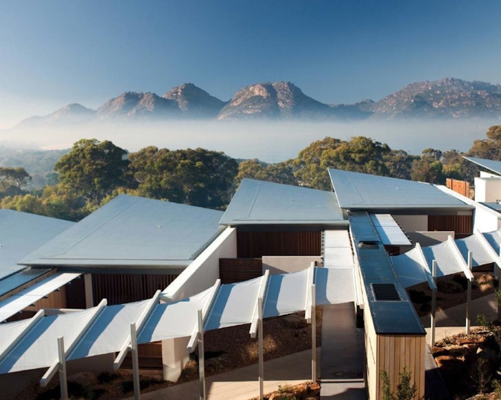 An exterior view of accommodation with mountains in the background at Saffire Freycinet one of the best hotels in Australia