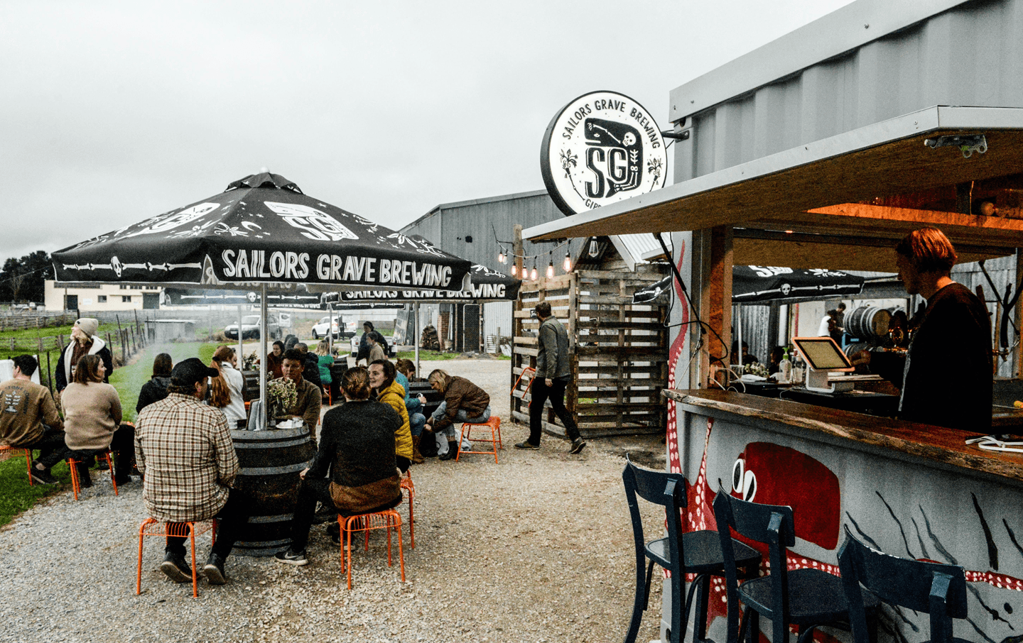 An outdoor beer garden with people drinking an a bar.