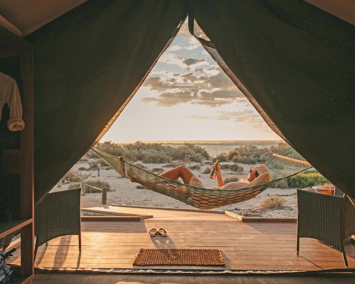 A guest lies in a hammock at the entrance to a tent at Sal Salis one of the best romantic getaways in Australia
