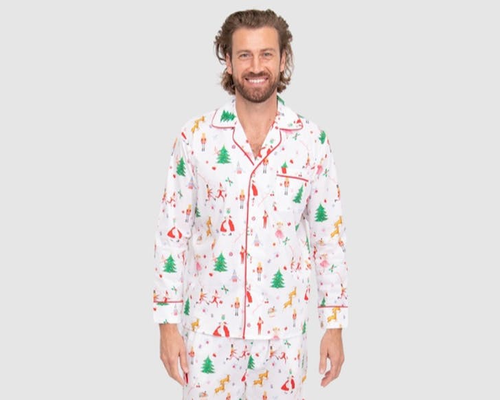 A man wears a white pyjama set covered in Christmas icons. 