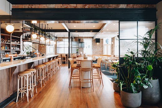 The interior of the pub with wooden floors a long bar and plants.