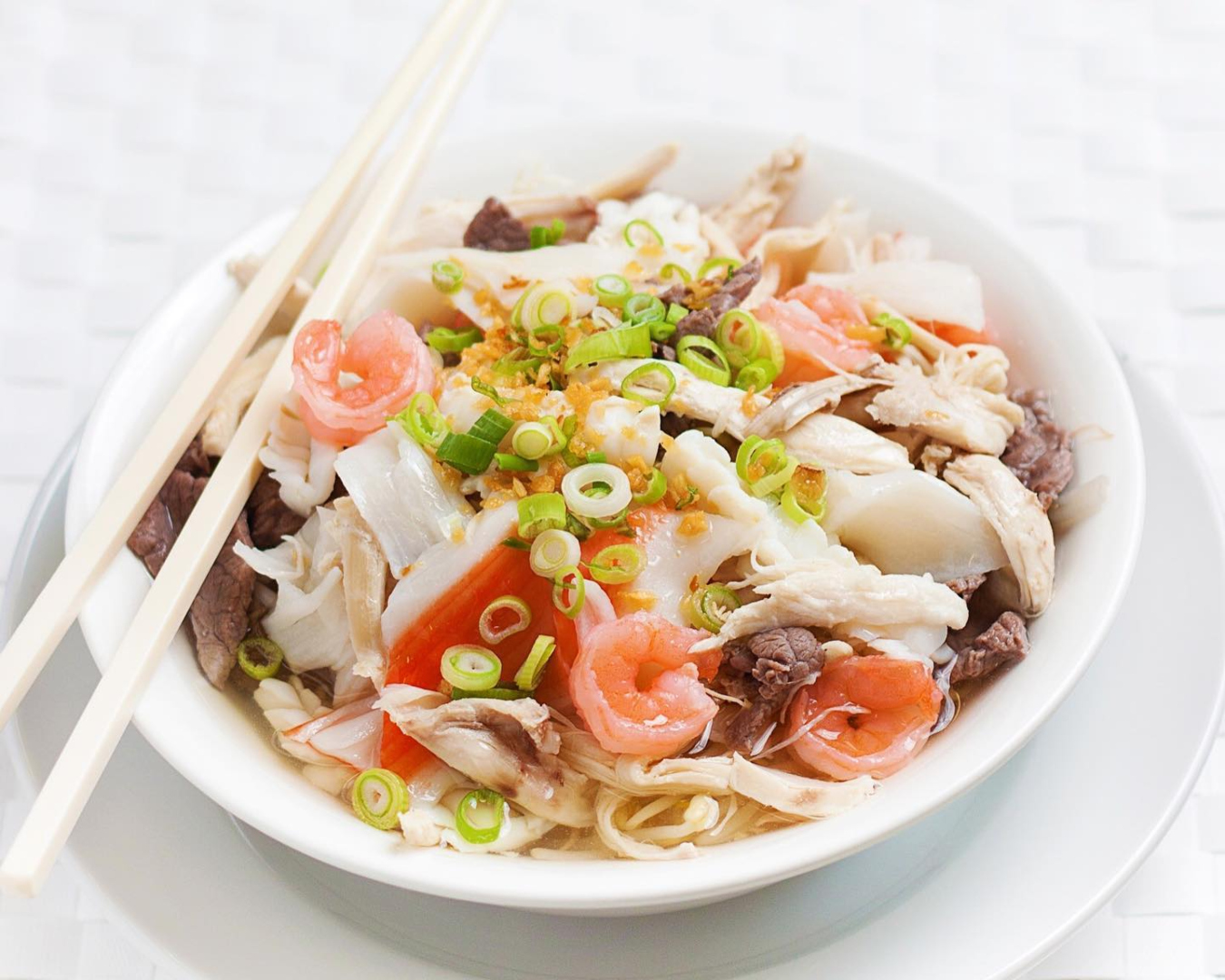 A bowl filled to the brim with noodles, broth and other goodies. 