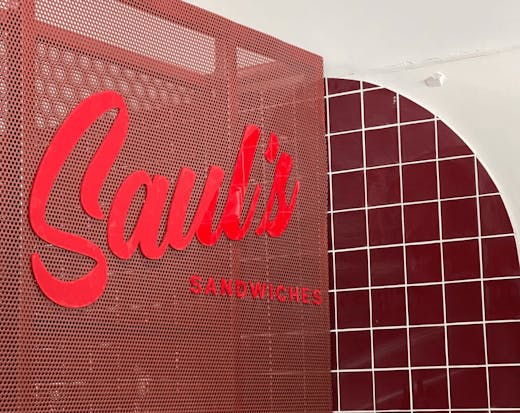 A large red Saul's sign and red checkered tiles on a white wall.