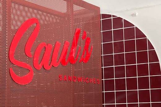 A large red Saul's sign and red checkered tiles on a white wall.