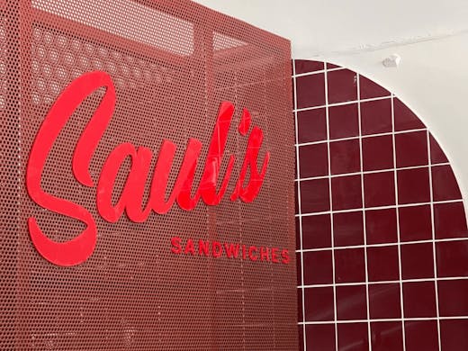 A large red Saul's sign and red checkered tiles on a white wall.