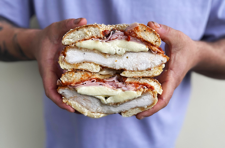 a large sandwich filled with chicken and cheese, held in two hands.