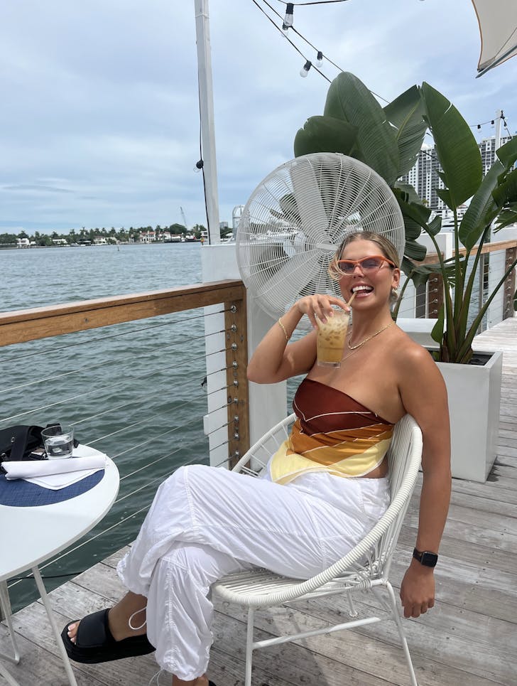person holding cup in front of water