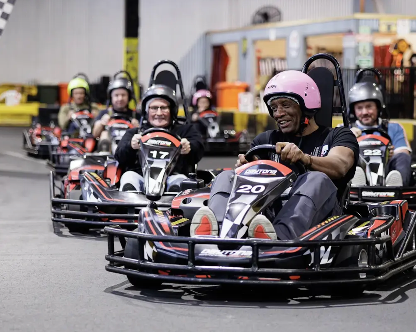 A wide shot of a group of people beginning their go-kart race at Daytona Adventure Park. They are all smiling.