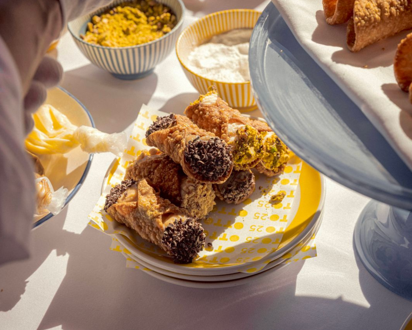 Close up image of the Boozy Dolci cannolis presented nicely on a plate. The image is taken outdoors with natural light shining on the table that the cannolis are placed on.