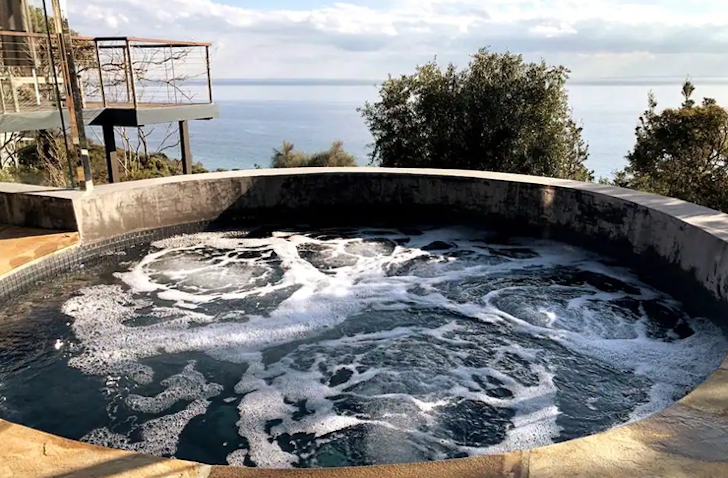 A large rounded spa has its jets turned on while overlooking views of the ocean