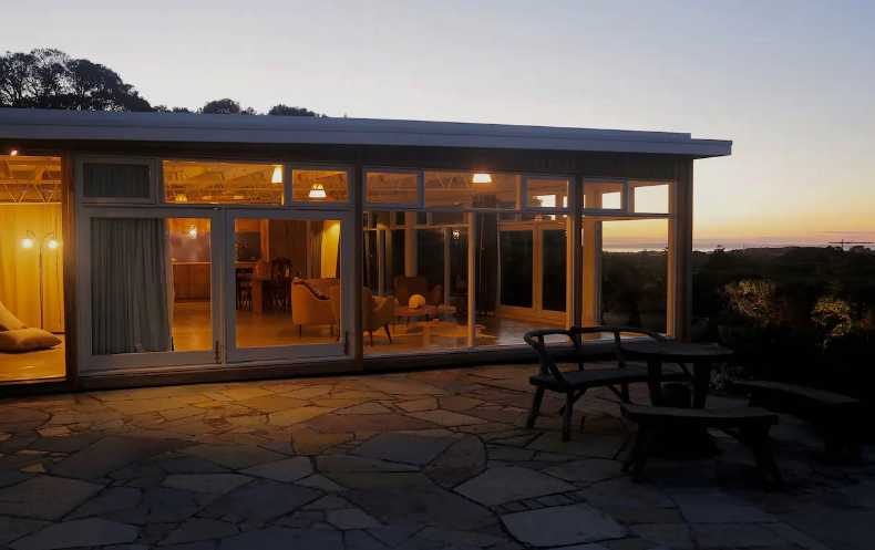 One of the best airbnbs in Victoria lit up at night overlooking the bay.