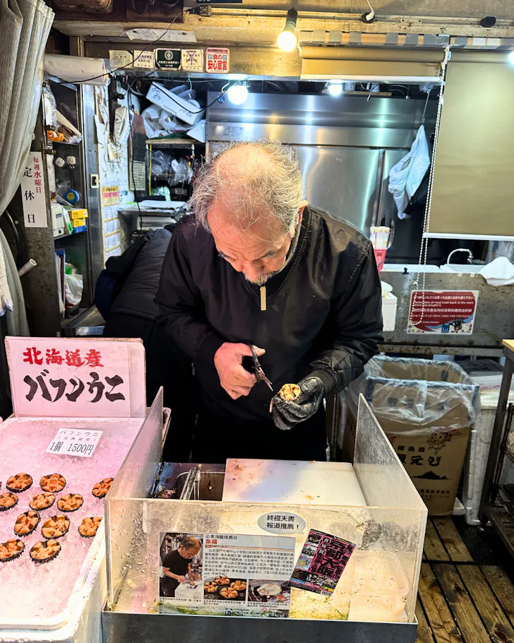 A storeowner opening a sea urchin in front of customers in Dotonbori Osaka.