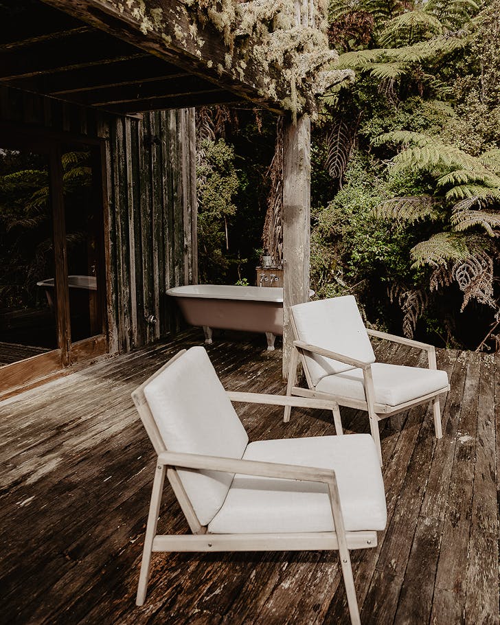 The outdoor space of a secluded accommodation shows a bath in the background.