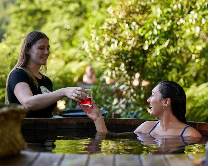 A person is served a drink while relaxing in a Secret Spot Hot Tub. 