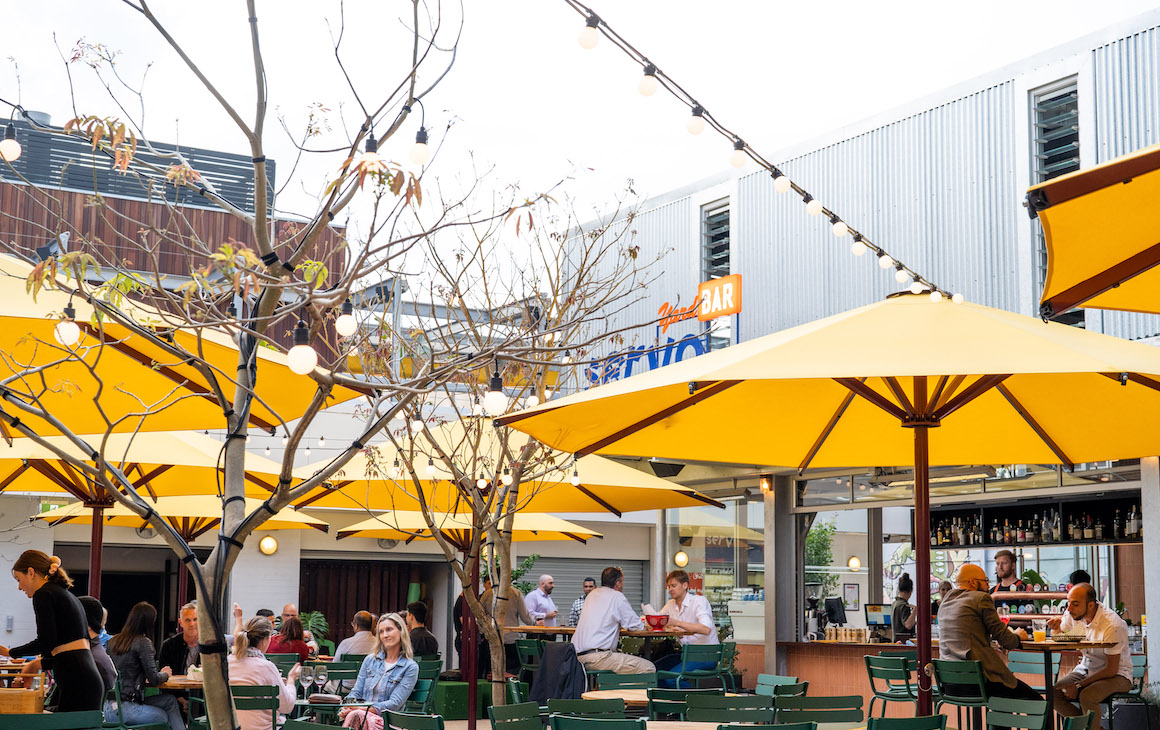 an outdoor area with green tables and yellow umbrellas