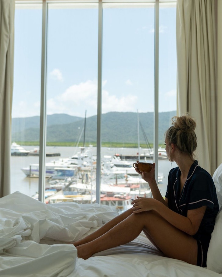 A woman looks out the window at the boats at Shangri-La The Marina one of the best hotels in Cairns