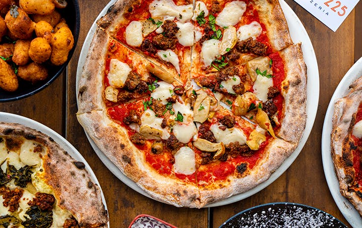 A table with different dishes and pizzas at a best pizza melbourne restaurant. 