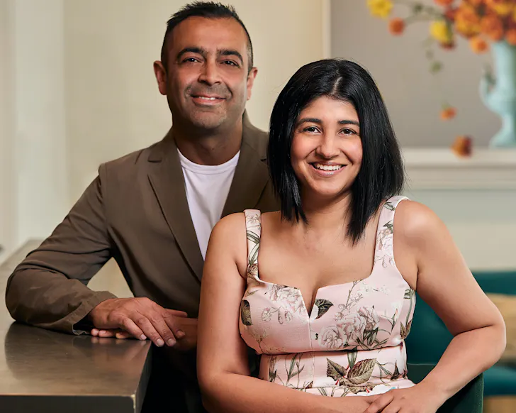 Sid and Chand sit together smiling. 