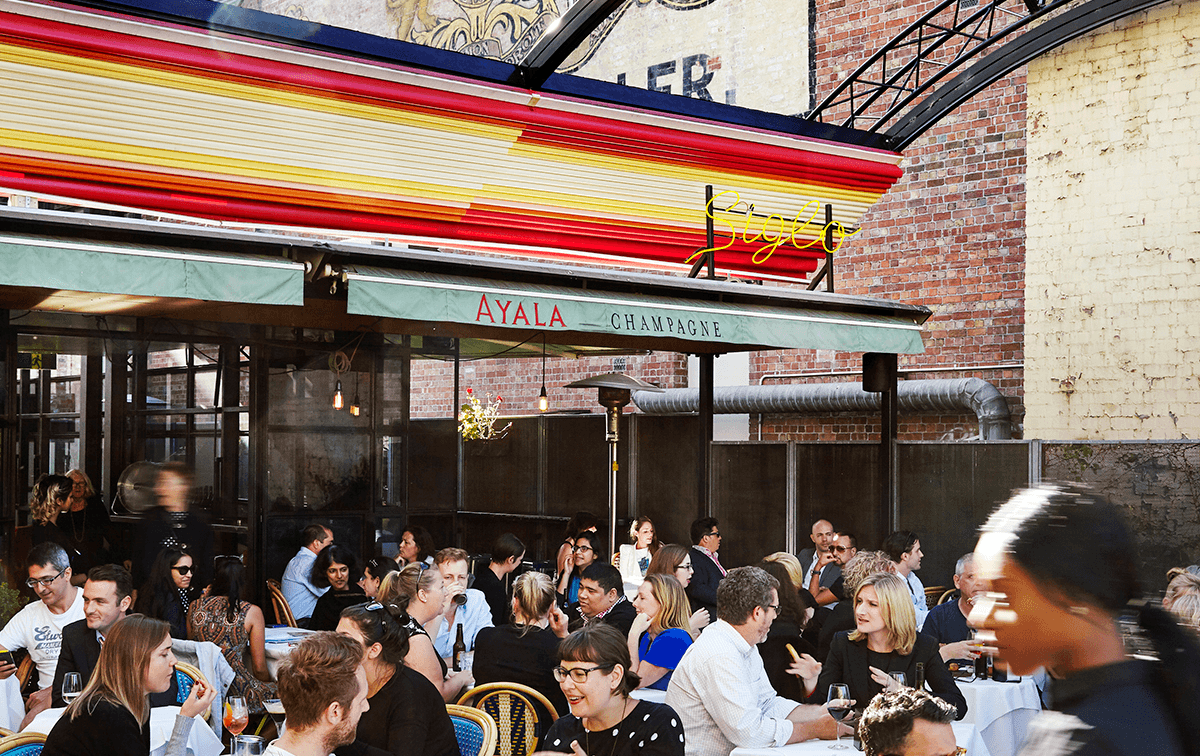 Groups of people drinking in the sun under awnings at one of the best bars in Melbourne. 