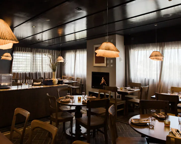 A warm, earthen-toned restaurant setting with a fireplace. 