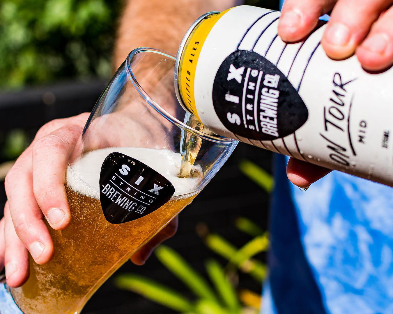 Hand pouring beer can into schooner glass